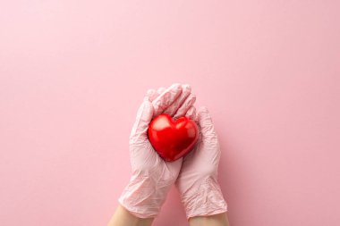 Kadın eldivenli ellerin pastel pembe bir arka planda kırmızı bir kalp sallamasını ilk gören kişi şeker hastalığının farkındalığını simgeliyor. Metin veya reklamlar için geniş alan