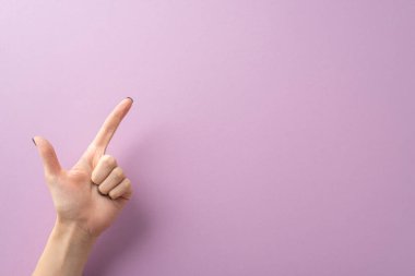 Genç bir kadının eli, parlak siyah tırnaklarla süslenmiş, işaret ve baş parmağını kullanarak tabanca jesti yapıyor. Metin veya reklamlar için alan sağlayarak, leylak yüzeyinde birinci şahıs görüntüsünden yakalanır