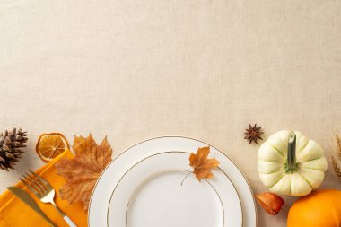 Şükran Günü tablosu ilham kaynağı. Tabaklar, çatal, bıçak, balkabağı ve sonbahar dekorasyonları Pastel bej masa örtüsünün üstünden düzenlenmiştir. Mesaj ve reklamlar için yer bırakılır.