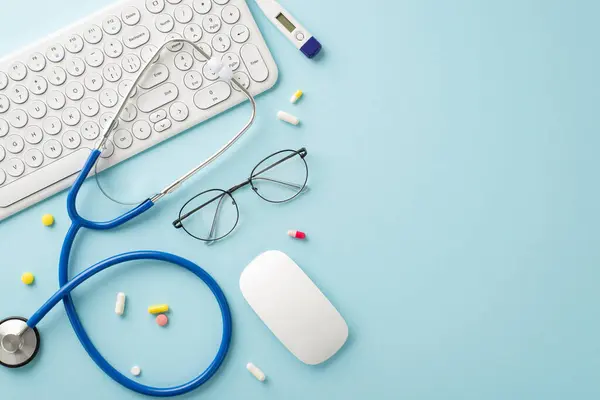 Embrace the future of medical care online. Overhead shot of a pc keyboard, computer mouse, stethoscope, eyeglasses, thermometer, pills on a pastel blue surface, ready for your branding or message