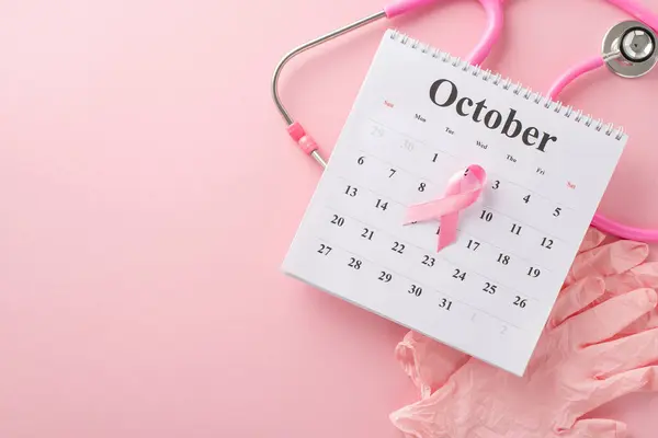 Breast cancer screening date. Top-view perspective of pink surgical gloves, stethoscope, and October calendar featuring pink ribbon on pastel pink setting, offering space for your messaging or advert