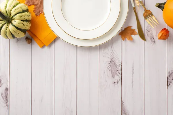 The fall-inspired concept of a Thanksgiving feast in aerial shot. Gilded table settings and seasonal decorations embellish a white wooden isolated backdrop, featuring ample space for text or adverts
