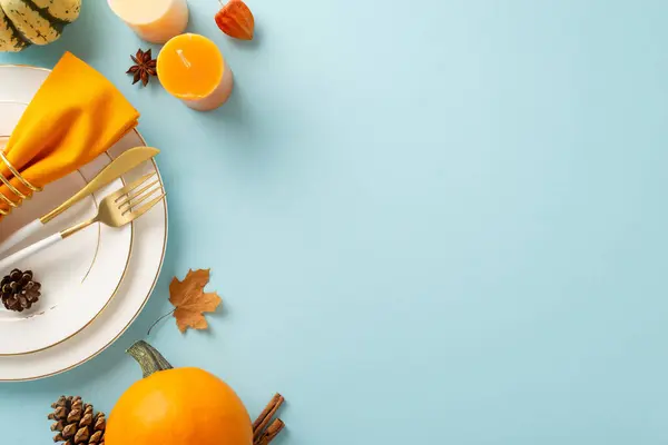 Fall-inspired Thanksgiving feast is portrayed from an aerial standpoint. Gilded table settings, vintage cutlery and decor on light blue isolated backdrop, ample space for text or adverts