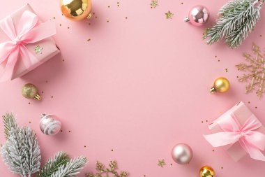 Zarif tatil büyüsü fikri. Fiyonklu hediye kutularının üst görüntüsü, güzel ağaç süsleri, ışıldayan kar taneleri, pırıl pırıl pullar, açık pembe arka planda donla kaplı köknar dalları, tanıtım için çerçeve.