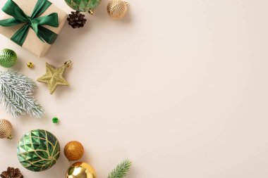 Neşelen: Üst bakış açısı, el işi kağıt hediye kutusu, parıldayan ağaç süslemeleri, yeşil, turuncu ve altın takılar, yıldız dekoru, bej bej tuvaldeki buzlu köknar dalı, mesajınız için yer