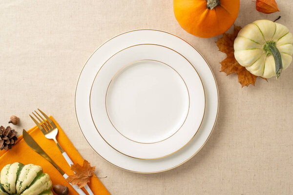 Thanksgiving feast arrangement: Top view shot of plates, napkin and cutlery on a beige tablecloth adorned with pumpkins, foliage, and pine cone. Delicate autumn vibes invite your text or message
