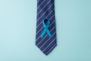 Erkek Sağlığı Savunucusu. Prostat kanseri farkındalığı ambleminin üst görüntüsü - kravatına iliştirilmiş mavi kurdele - yumuşak mavi arka planda, metin veya promosyonlar için yer var