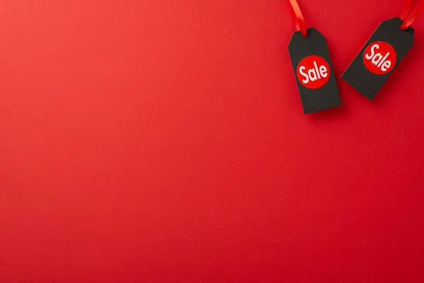 Economically-minded consumer Black Friday idea. Top view image of sale stickers on pricing tags against a bold red background, ready for promotional text or ads