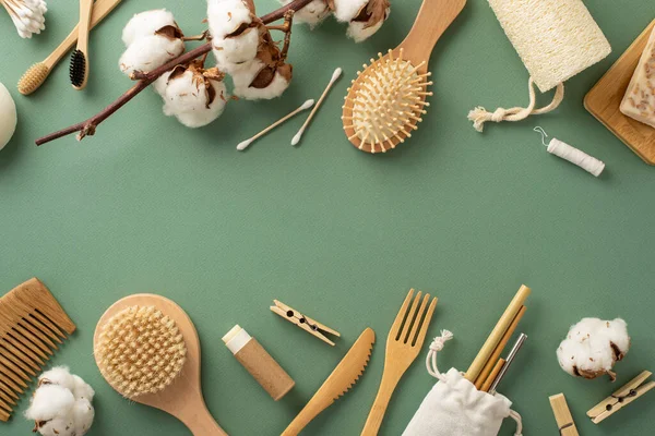 Earth-friendly essentials. Overhead view of bamboo toothbrushes, wooden straws, loofah washcloth, hairbrushes, clothespins and more eco-friendly items on calm green surface, ready for your branding