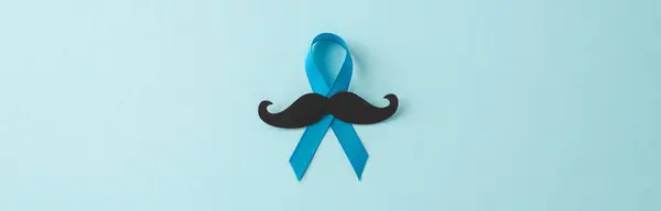Men\'s Health Awareness Month. Top view of prostate cancer symbols - blue ribbon with mustache silhouette on a pastel blue backdrop, ideal for text or ads