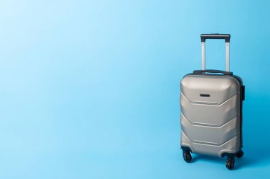 Pack and Go: Mavi bir yüzey üzerinde yandan çekilmiş şık bir seyahat valizi, metin veya promosyon içeriğiniz için hazır