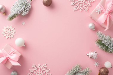 Gösterişli Tatil Düzenlemesi. Yay, ağaç süslemeleri, kar taneleri dekoru ile süslenmiş hediye kutularının genel görünümü ve pastel pembe alandaki buzlu köknar dalları metin veya promosyon için çerçeveli.
