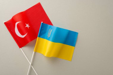 İkili ilişkiler: Tarafsız gri bir arkaplan üzerinde Ukrayna ve Türk bayraklarının yukarıdan çekilmiş görüntüleri, metin veya reklam için ideal bir tuval oluşturuyor