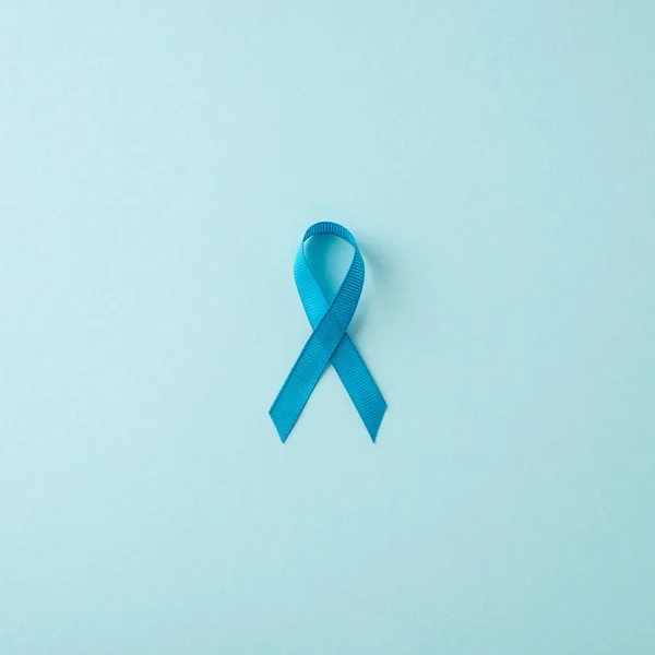 Men\'s Cancer Fight. Overhead shot of prostate cancer awareness icon - blue ribbon on a gentle blue background, suitable for text or promotional content