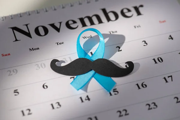 Highlighting Men's Health Month. Emblem of blue ribbon, mustache on November calendar for vital doctor check-ups promotion