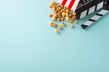 Film şeridi için heyecan verici bir fikir. Yönetmenin alkış görüntüsü, çizgili ambalajlı nefis patlamış mısır, mesaj iletmek için boş alanı olan soluk mavi bir yüzeye ayarlı
