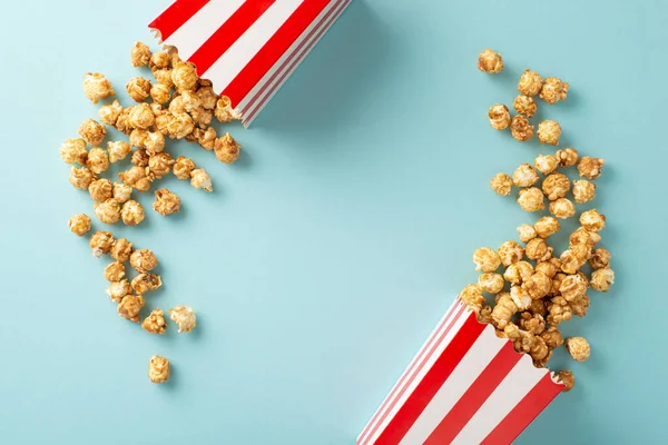 Eagerly awaiting movie reel premiere. Top view perspective snapshot of tasty popcorn in two striped boxes against a light blue backdrop for text or advertising