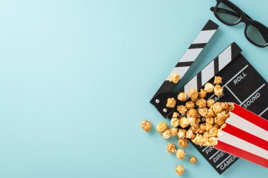 Film şeridinin açılmasını bekliyorum. Bir film yapımcısının el çırpma tahtasının üst görüntüsü, 3D gözlükler, çizgili paketten yayılmış nefis patlamış mısır, açık mavi bir arka planda, metin veya tanıtım için yer var.