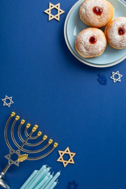 Hanukkah-themed vertical top view table setting with sufganiyot, menorah, candles, and the Star of David symbols on a blue background, perfect for your celebration clipart