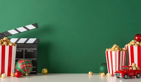 Celebrate Christmas at home with delightful popcorn delivery setup. Capture side view of table with tiny car, striped popcorn boxes, balls, green wall backdrop, providing perfect spot for movie promo