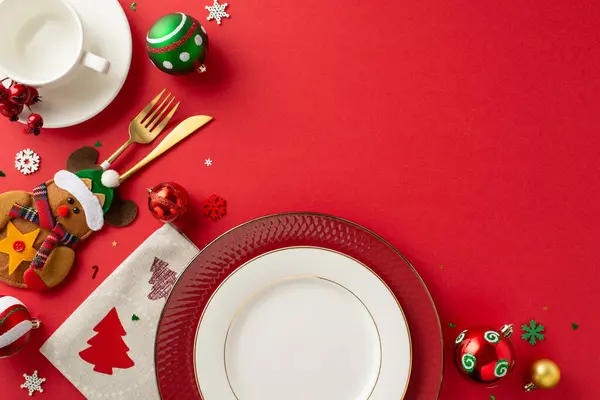 Organize inviting New Year\'s dinner table scene. Top view of dishes, gold utensils in charming pocket, napkin, mug, baubles, snowflakes on crimson backdrop with open space for text or advertisement