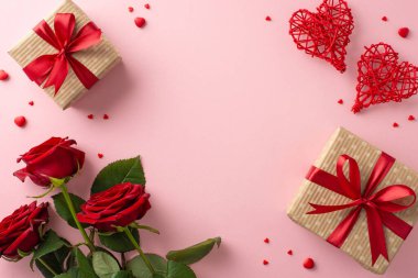 Sevgililer Günü 'nde aşkı kutlayalım. Büyüleyici el sanatları, kağıt hediye kutuları, rattan kalpler, kırmızı güller, üzerine şeker serpiştirilmiş pastel pembe arka plan serpiştirilmiş, metin ve reklamlar için idealdir.