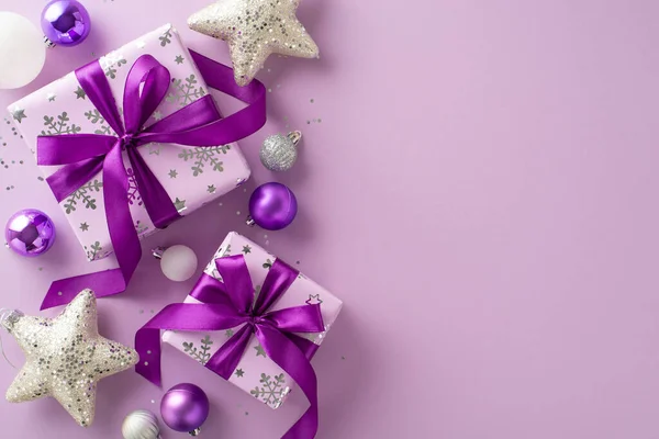 Extend your warm wishes with this delightful gift arrangement. Top view of exquisite lavender gift boxes, festive ornaments, sparkling stars, sequins on purple backdrop, leaving space for your message