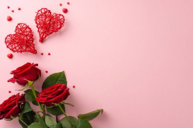 Sevgililer Günü kompozisyonu, el yapımı rattan kalpler, bir demet kırmızı gül, ve pastel pembe üzerine şeker serpiştirilmiş şeker, metin veya promosyon içeriği için alan