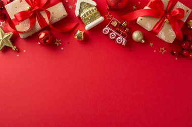 Noel atmosferine geri sayım. Kırmızı ve altın süslemelerle süslenmiş kırsal hediye kutuları, büyüleyici ağaç ıvır zıvırları, ökseotu, konfeti, mesajınız için kırmızı arkaplanda yer var.