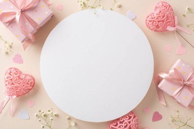 Aşkı, hediye kutuları, çingeneler, kalp şeklinde konfetiler ve sopaların üzerindeki kalplerle kutlayın. Pastel bej arkaplan metin veya promosyon için boş daire sunar
