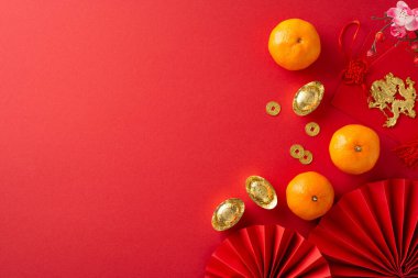 Bir çerçevedeki Çin Yeni Yılı esasları: hayranların üst görüntüsü, Feng Shui ıvır zıvırları, madeni paralar, sicee, kırmızı zarflar, ejderha tılsımı duvarlar asılı, kırmızı yüzeyde mandalinalar, yazı ve reklamlar için ideal bir yer sunuyor