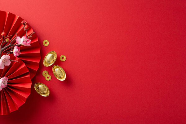 Embrace the Lunar New Year atmosphere: Top-view shot of fans, Feng Shui items, lucky coins, sycee and sakura on a red background, offering ample space for text or adverts