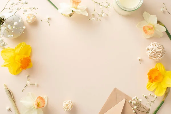 Extend your warmest wishes for spring with narcissus and gypsophila. Top view image captures flowers, an envelope and candle on a beige isolated backdrop creating an inviting space for adverts or text