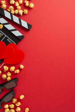 Sevgililer Günü fikri: alkış tahtası, 3D gözlükler, çıtır çıtır patlamış mısır ve kırmızı bir arkaplanda kalp şeklindeki dekor romantik bir film maratonu sahnesi hazırlıyor.