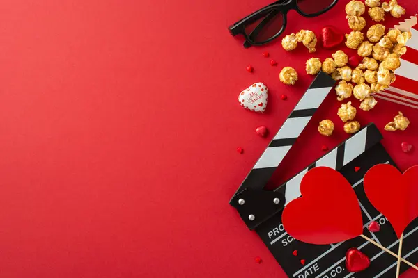 Cinematic Love Affair: Top-down view of a clapperboard, 3D glasses, scattered popcorn, candies, sprinkles and heart-themed decor, setting the stage for romantic film premiere on a vibrant red surface
