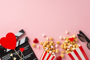 Aşk dolu film gecesi. Clapperboard, 3D gözlükler, çizgili patlamış mısır kutuları, kalp temalı dekorasyonlar, şekerlemeler, büyüleyici pastel pembe arka planda düzenlenmiş şekerlemeler.