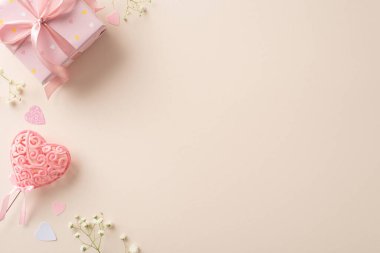 Sevgililer Günü cazibesi yukarıdan gösterildi: hediye kutusu, gypìila, kalp şeklinde konfeti ve kalp çubuğu. Mesajınız için boş tuval içeren bej rengi bir arkaplan