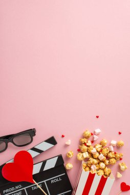 Aşk dolu film tarihi: Dikey çekim tahtası, 3D gözlükler, patlamış mısır, kalp dekoru, lokum ve tatlı pastel pembe arka plan üzerine serpiştirilmiş şekerlemeler. Romantizm sahnesini hazırla