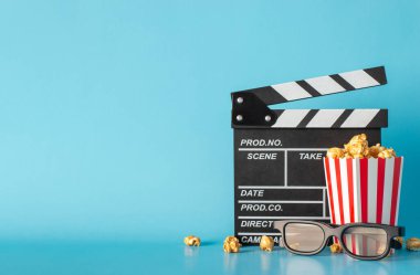 Uzun zamandır beklenen ilk filmin heyecanını yaşayın. Yan görünüm masa sahnesini el çırpma tahtası, çizgili patlamış mısır kutusu ve açık mavi duvara dayanan 3D gözlüklerle yakalar, mesaj veya film reklamları için yer bırakır