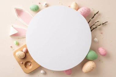 Dive into Easter spirit with heartwarming arrangement. Top view of festive eggs, whimsical bunny ears, delicate pussy-willow branches, sprinkles on pastel canvas, leaving circle for your text or promo