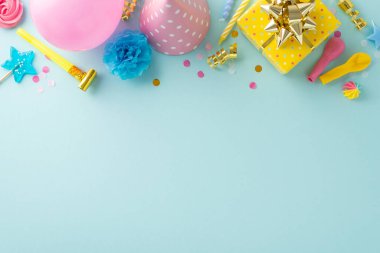 Şenlikli doğum günü partisi fikri. Hediyeler, doğum günü şapkaları, pipo, mumlar, balonlar, şekerler ve pastel mavi bir yüzeye konfetilerle süslenmiş bir masanın üst görüntüsü. Metin veya promosyonlar için geniş alan