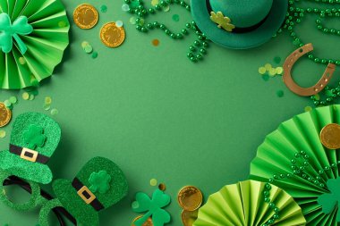 Festive St Patrick's top view scene: leprechaun's hat, whimsical glasses, lucky horseshoe, gold coins, fans, clovers, confetti, beads necklace arranged on green surface, leaving space for your message clipart