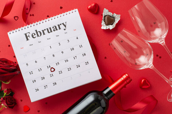 Valentine's Day countdown:top view February calendar, chocolates, wine, glasses, roses, silk ribbon, and confetti arranged on a vibrant red surface. Perfect for expressing love