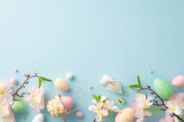 Paskalya Lezzetleri Düzenleme: küçük sepetteki parlak yumurtaların üst görüntüsü, sevimli tavşanlar, elma çiçekleri, ve pastel gökyüzü mavi yüzeyinde şeker parçacıkları. Metin ya da reklam için boşluk