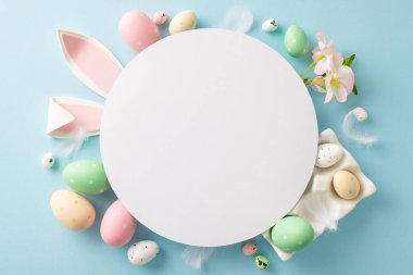 Yumurta sarısı bahar sahnesi: kabın içindeki renkli yumurtaların üst görüntüsü, büyüleyici tavşan kulakları, elma çiçeği, pastel mavisi arka plandaki yumuşak tüyler. İletiniz için yuvarlak çerçevede boşluk aç