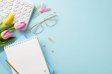İş dünyasında güçlendirme: Kadınlar Günü için ofis masası üst görünümü klavye, moda gözlükler, defterler, dolma kalemler, klipler ve taze laleler içerir. Bir ileti için boşluk içeren Pastel mavi ayarı