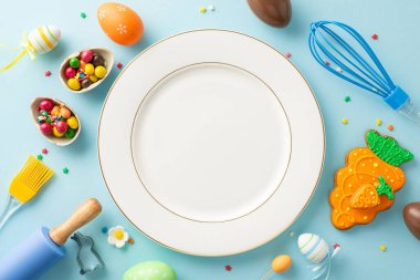 Paskalya için şekerleme atölyesi hazırlıyorum. Plaka, çırpı, pim, fırça. Tatlı zencefilli ekmek, çikolatalı yumurta, şeker, açık mavi yüzeyde serpiştirilmiş şeker. Metin için geniş alan