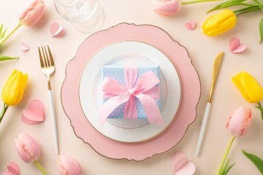 Kadınlar Günü ziyafeti konsepti. Rafine tabaklar, gümüş eşyalar, şarap kadehleri, çekici laleler, hediye ve açık bej tabanlı kalpler, reklam için ideal.