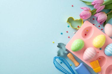 Şekerleme mutfağında paskalya eğlencesi. Fırça, raptiye ve fırçayla pişirmek için en iyi tablo manzarası. Kurabiye kesiciler, kabın içinde çikolatalı yumurtalar ve mavi arka planda daha fazlası. Metin için uygun alan