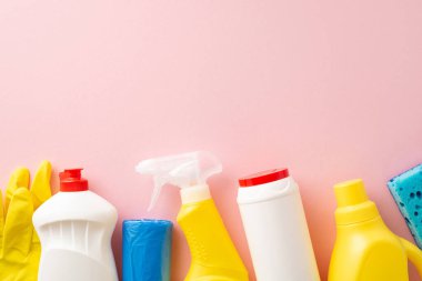 Ev temizliği için ideal, bu üstten çekim için uygun sprey, bulaşık deterjanı, bulaşık jeli, eldiven, çöp torbası ve sünger, yumuşak pembe bir zemin üzerine dizilmiş mesaj için yer.